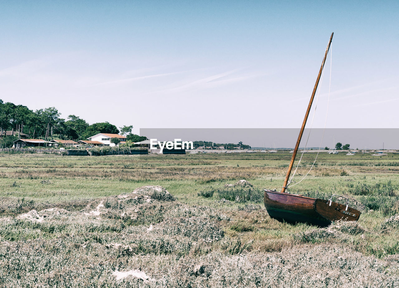 ABANDONED BOAT ON FIELD AGAINST SKY