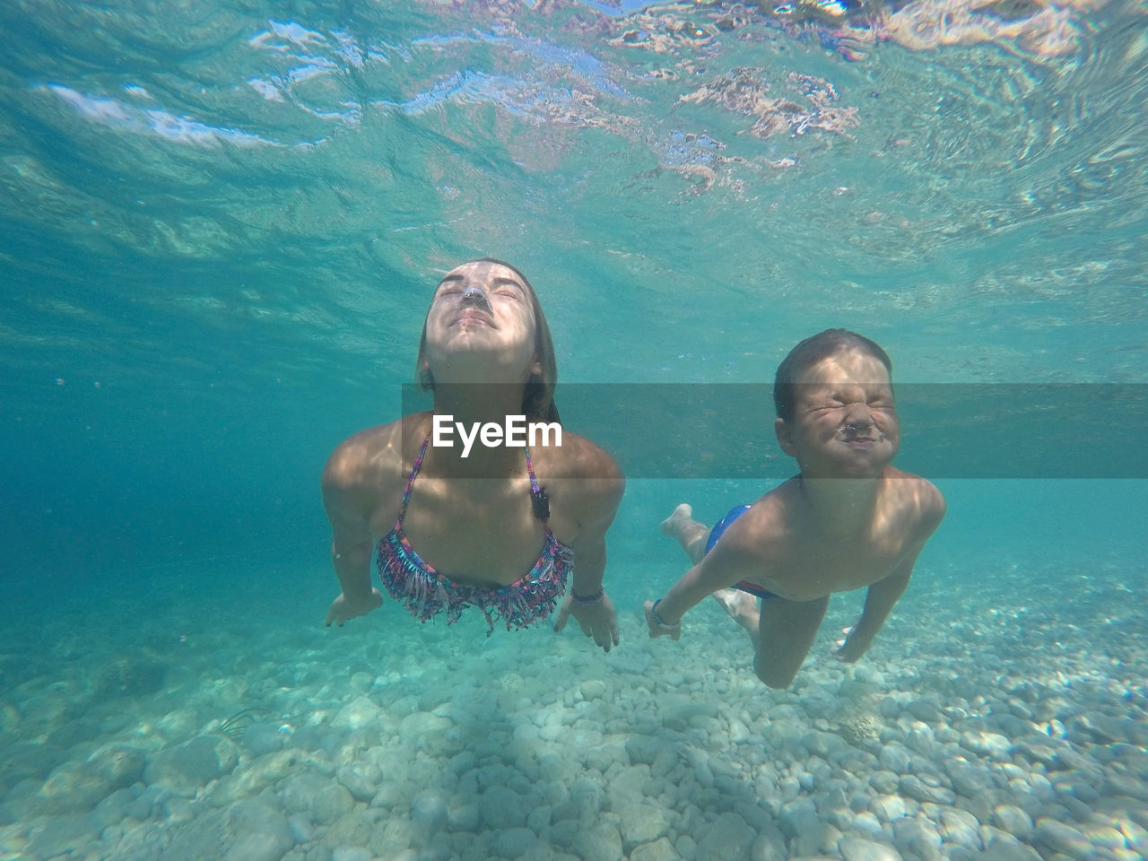 Young woman and boy holding breath underwater