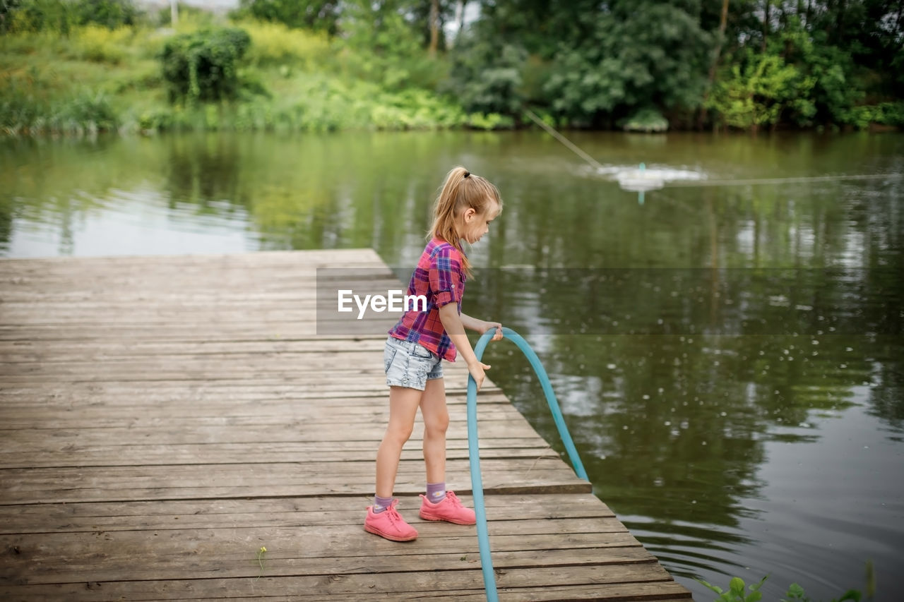 rear view of woman standing on pier over lake