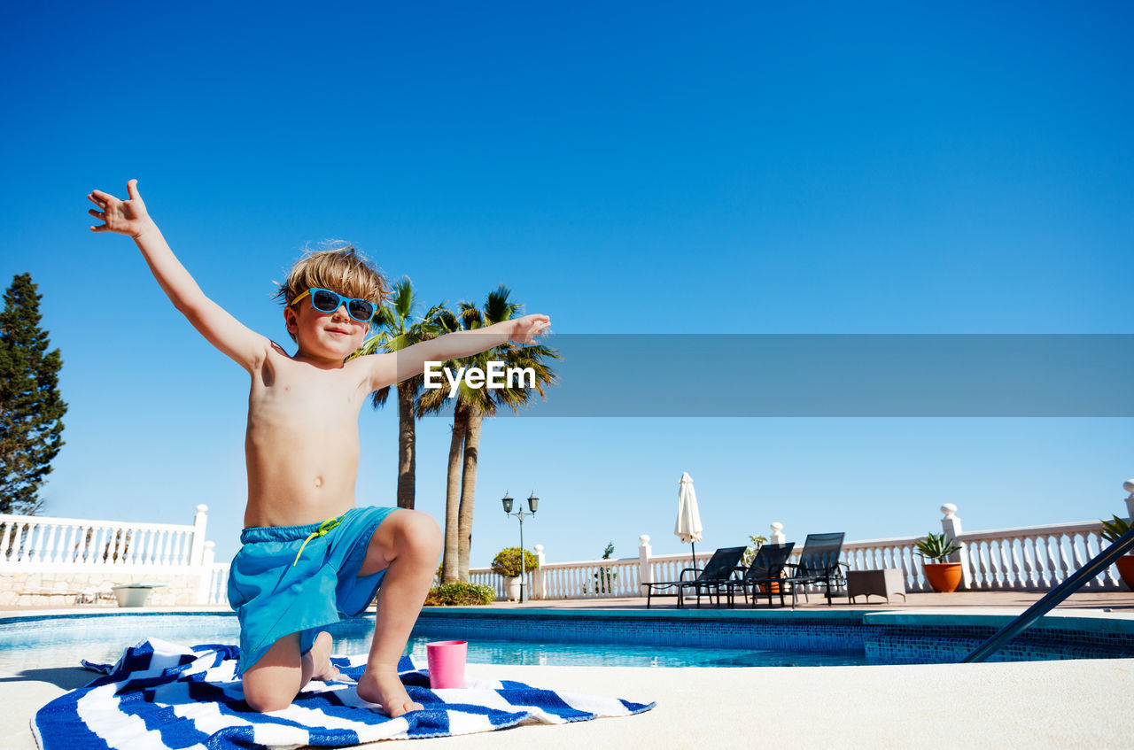 low angle view of woman jumping against clear blue sky