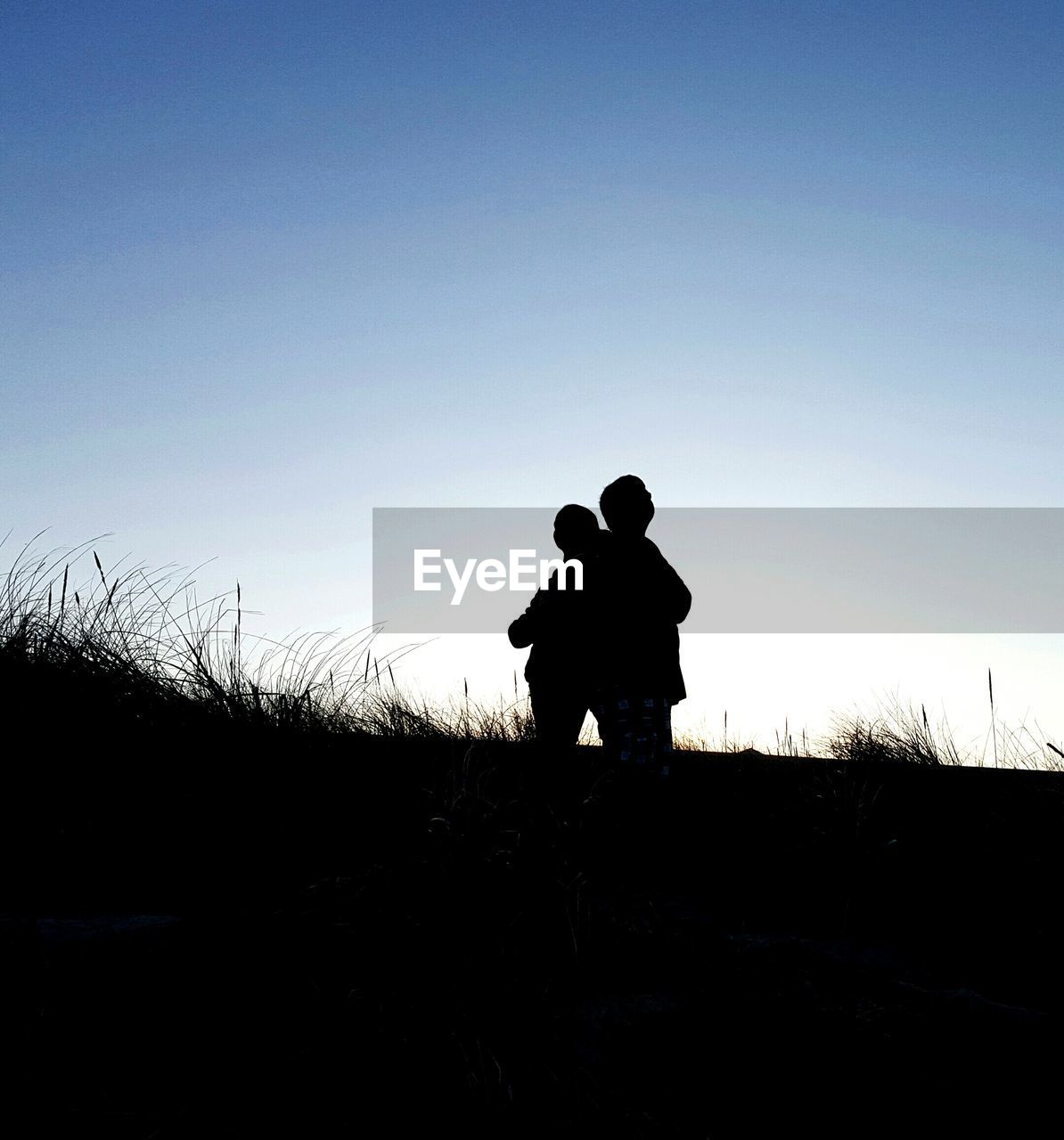 Silhouette of man standing on landscape against clear sky at sunset