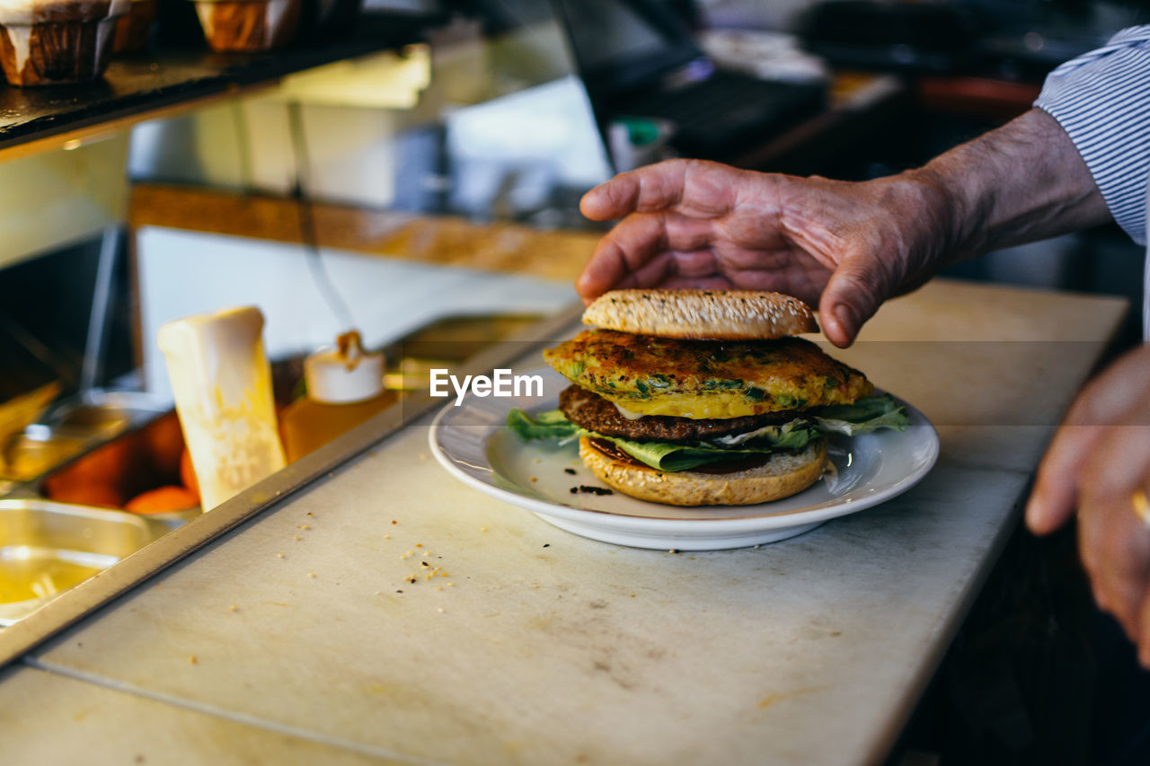 Midsection of man preparing burger in restaurant