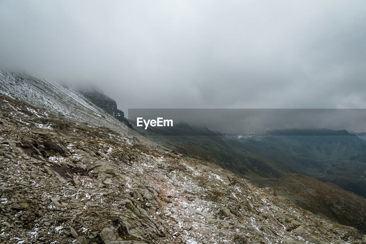 Scenic view of rocky mountains against cloudy sky