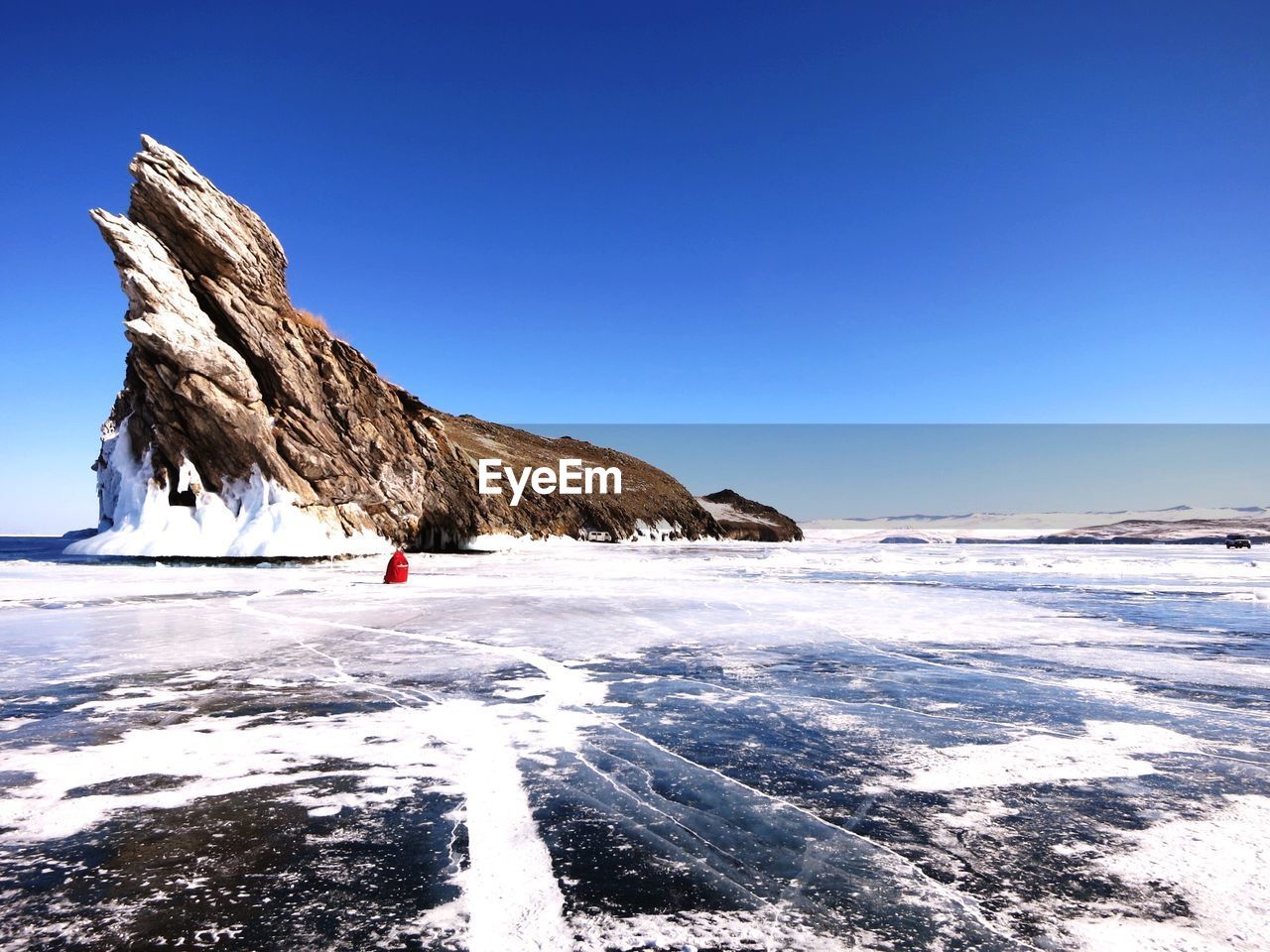 Scenic view of frozen lake against clear blue sky