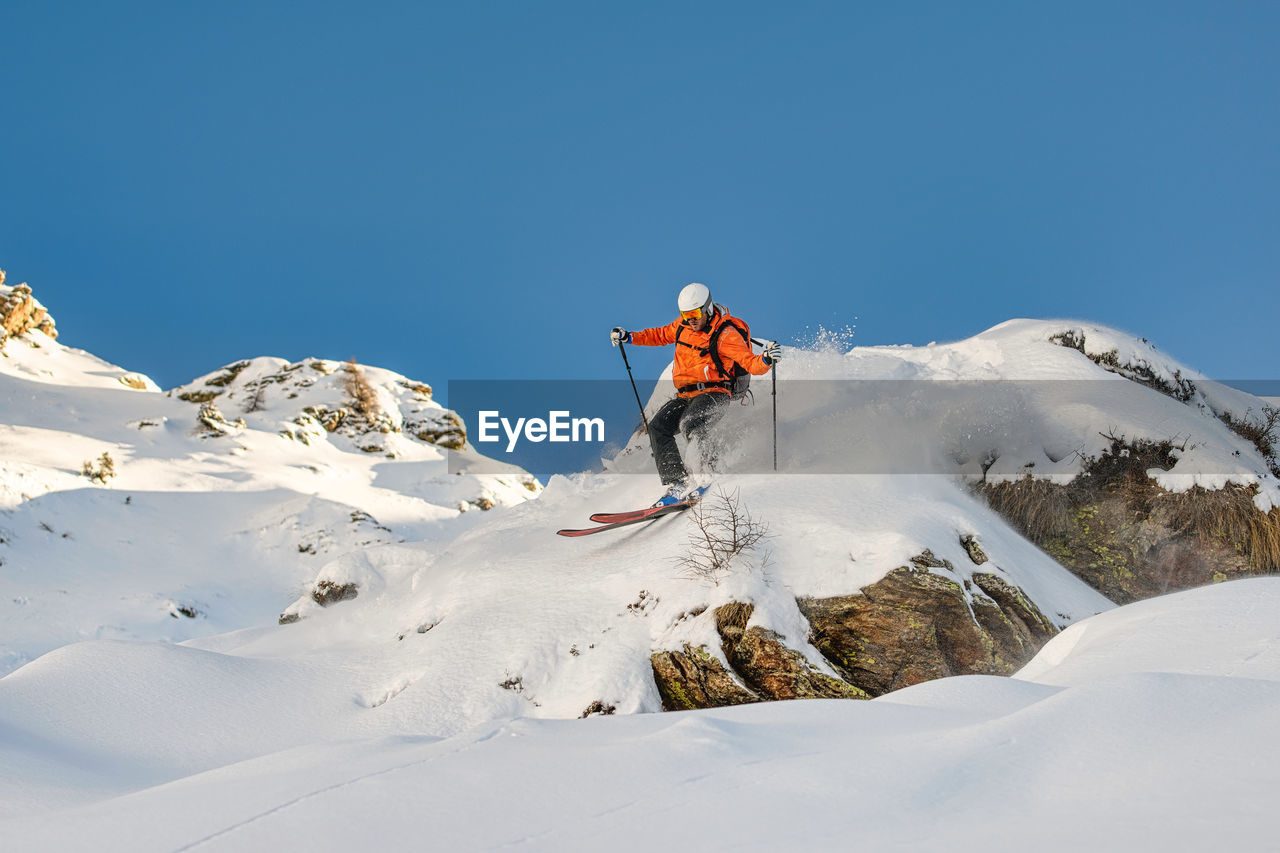 Free.rider skier descends between rocks on the italian alps