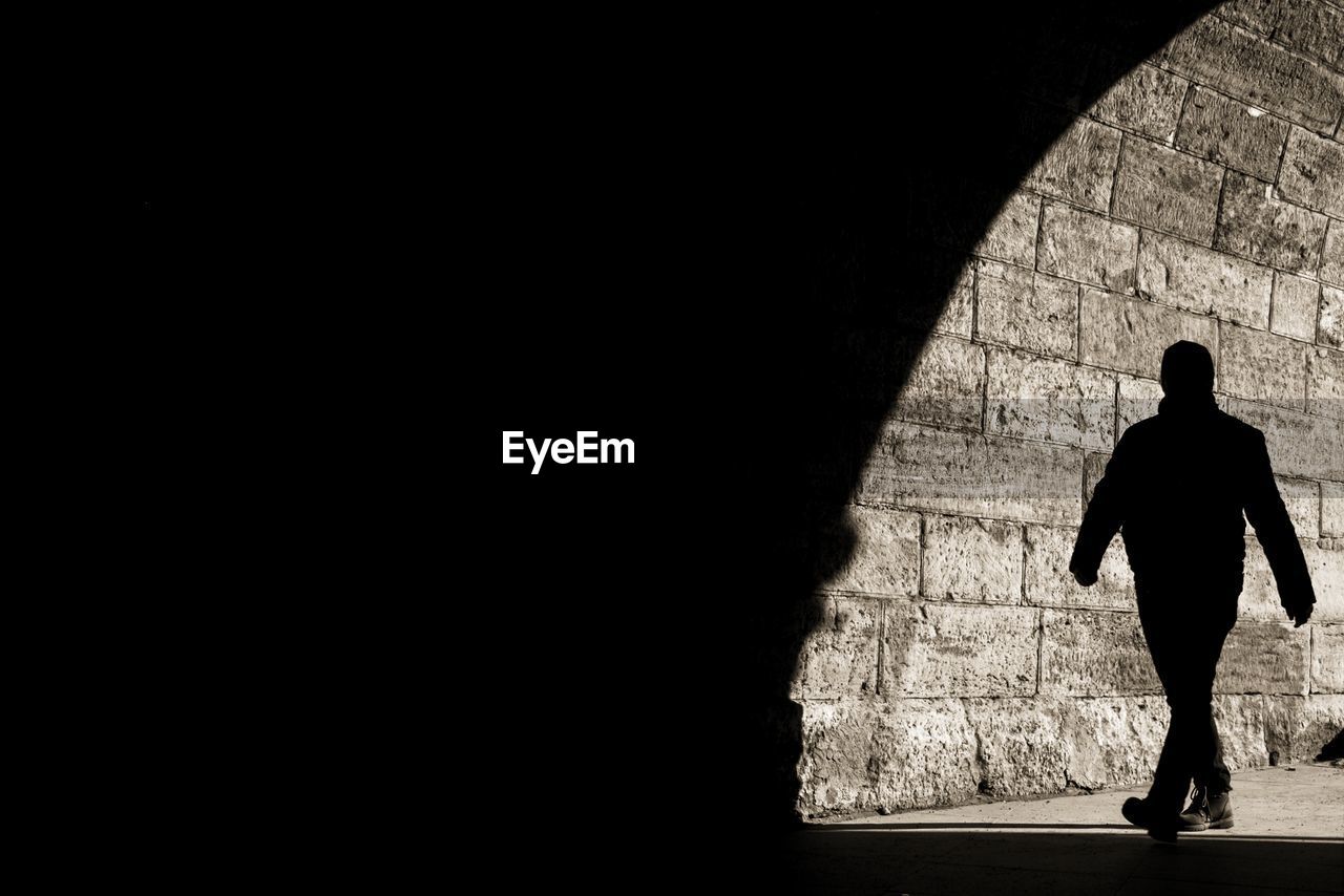 Full length of silhouette man walking on footpath in tunnel