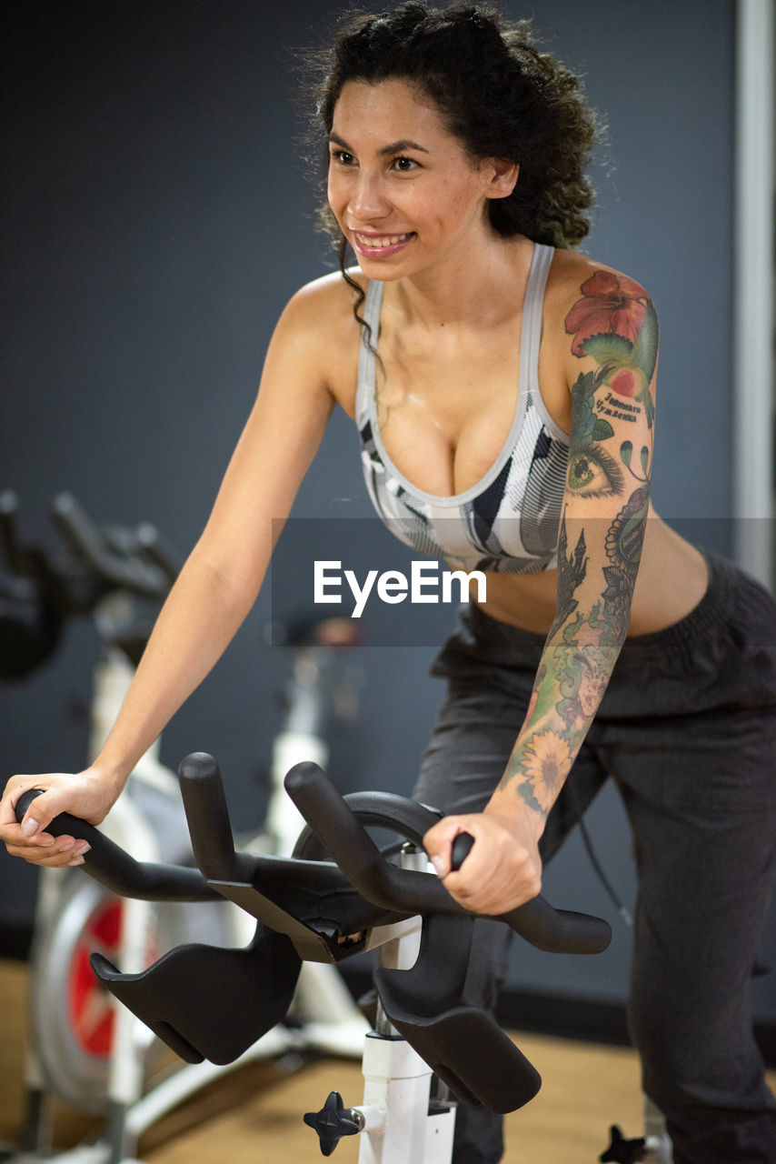 Young woman riding bicycle at the gym 