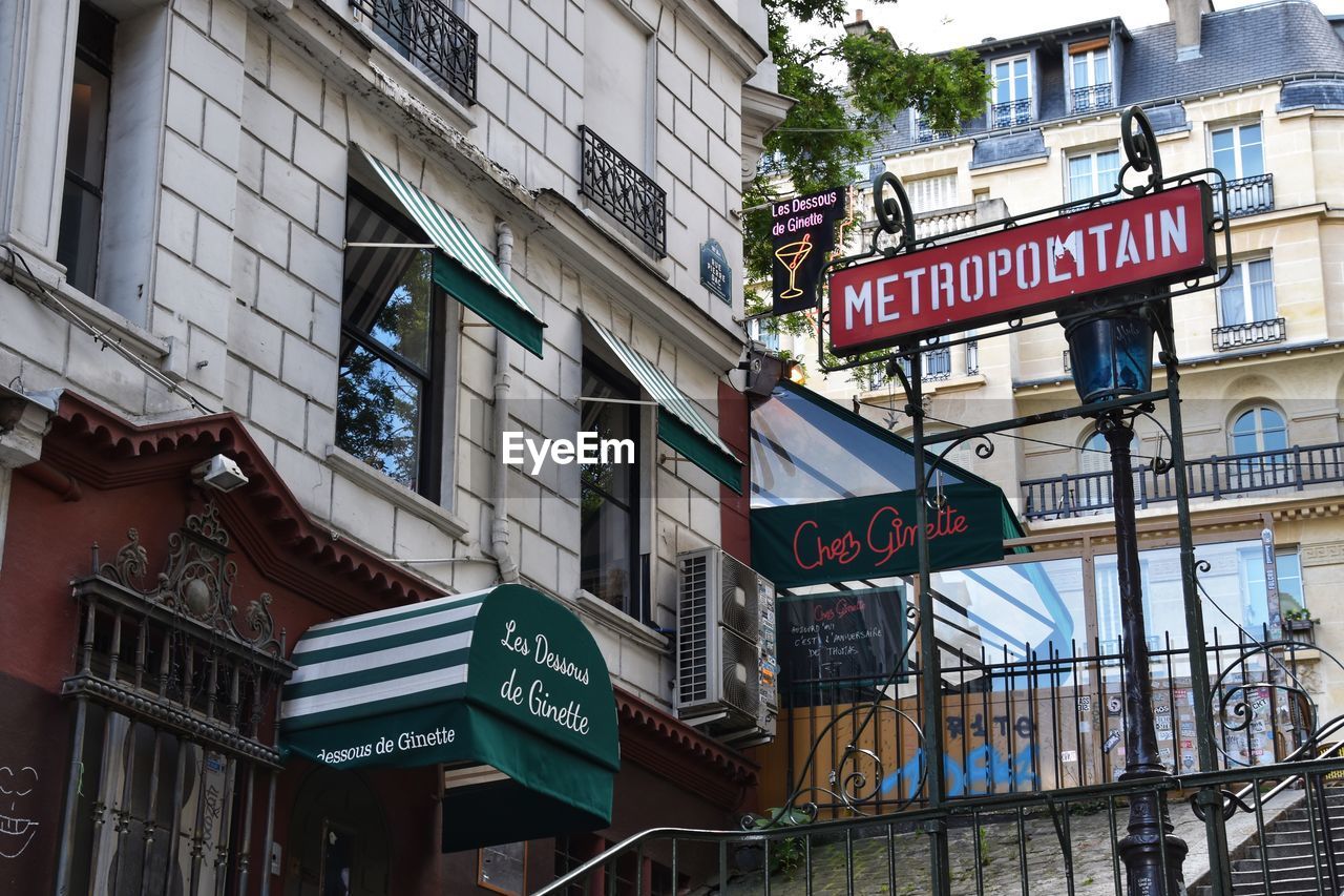 LOW ANGLE VIEW OF INFORMATION SIGN ON STREET AMIDST BUILDINGS