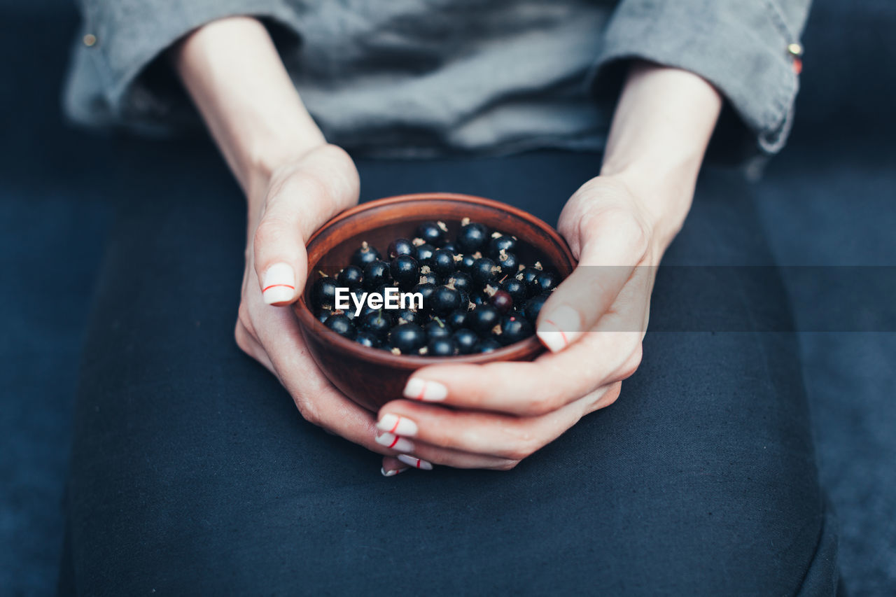 Midsection of woman holding currants in bowl