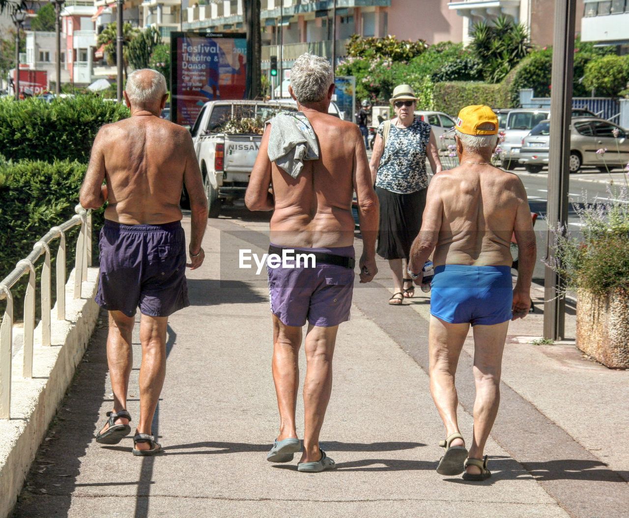 FULL LENGTH REAR VIEW OF MEN WALKING ON CITY STREET