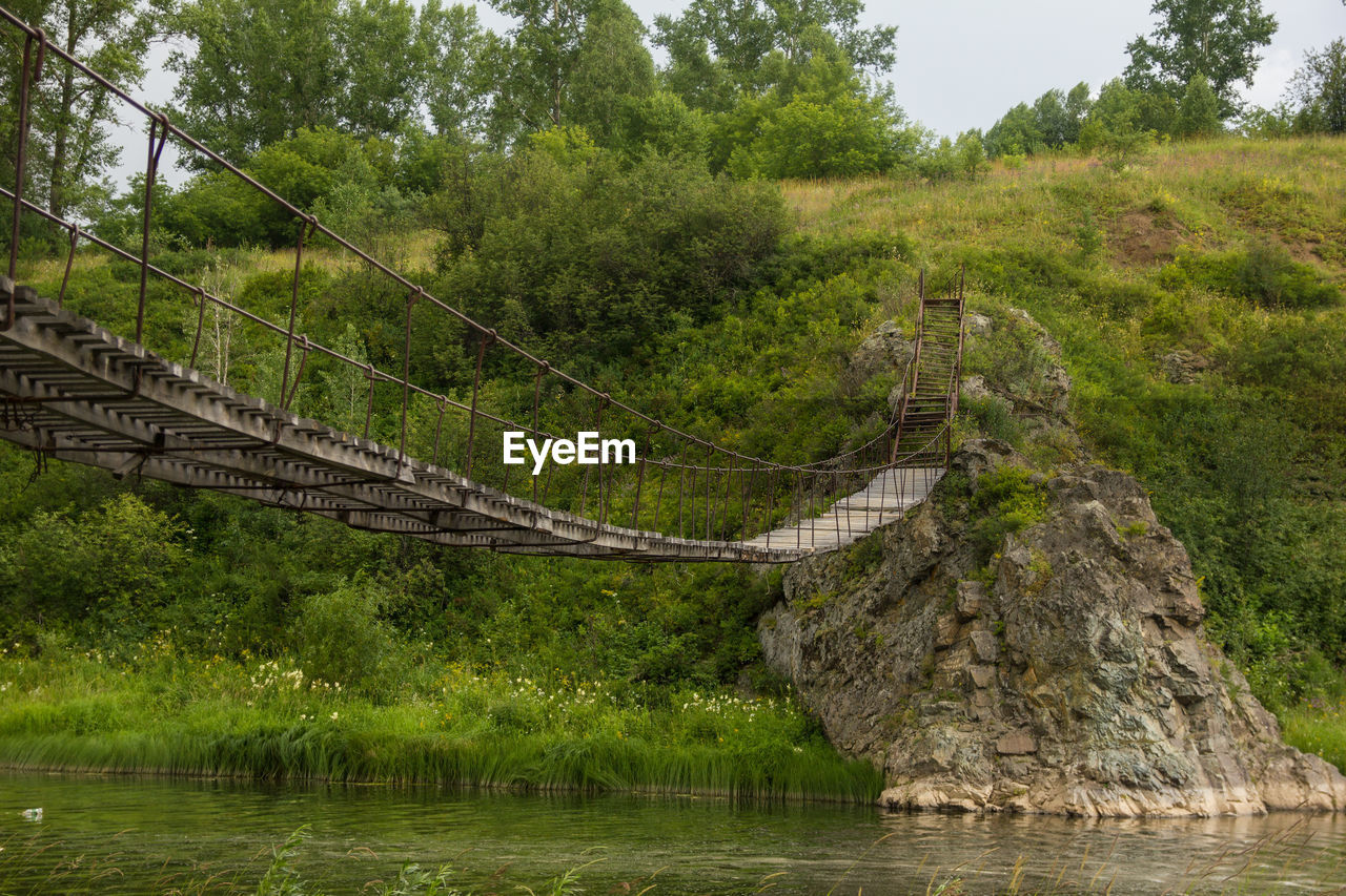 Old wooden suspension bridge over a small river