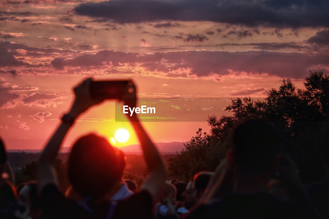 Person photographing sky during sunset