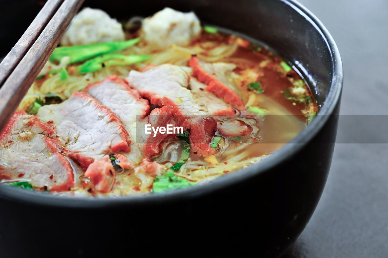 Close-up of noodle soup in bowl with chopsticks on table