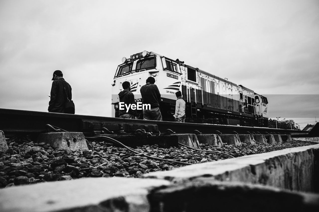 Locomotive on railroad track against cloudy sky