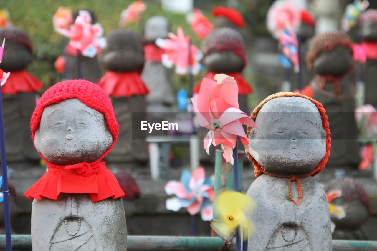 Close-up of pinwheels by stone sculptures at japanese shrine