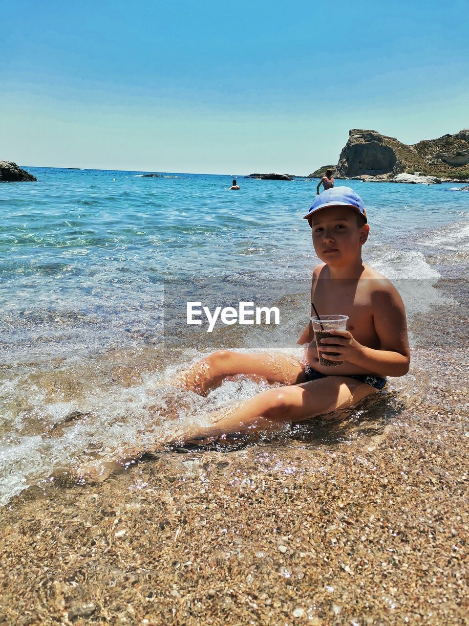 land, water, beach, sea, sand, vacation, shore, one person, nature, body of water, sky, leisure activity, coast, ocean, holiday, trip, sitting, beauty in nature, summer, lifestyles, relaxation, swimwear, clothing, sunlight, adult, day, full length, sun tanning, wave, young adult, sunny, women, horizon over water, outdoors, scenics - nature, child, portrait, hat, person, horizon, tranquility, clear sky, childhood, idyllic, bikini, sports, sunglasses, glasses, female, travel, fashion, looking at camera, rock, weekend activities, enjoyment, smiling, tranquil scene, men