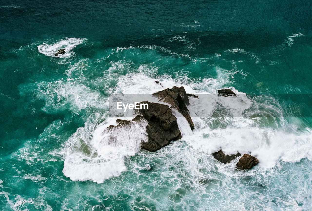 High angle view of waves crashing on rocks