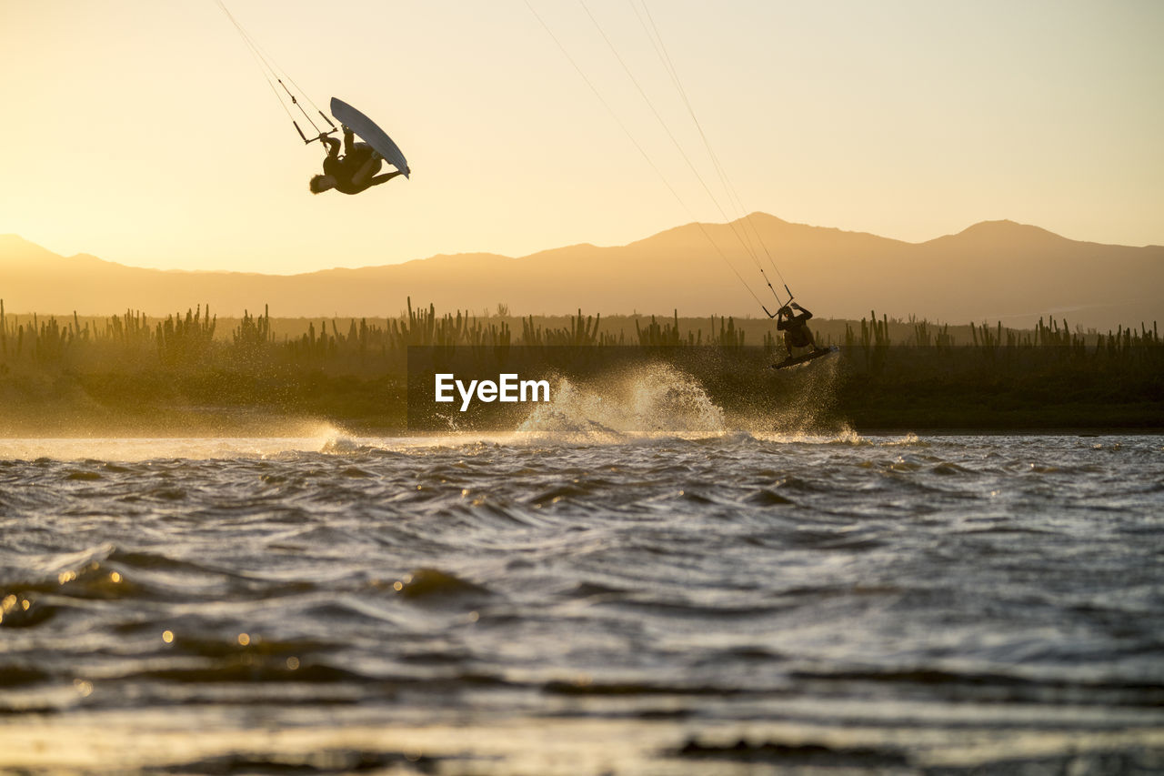 Young male athlete kiteboarding at sunset in la ventana, baja california, mexico