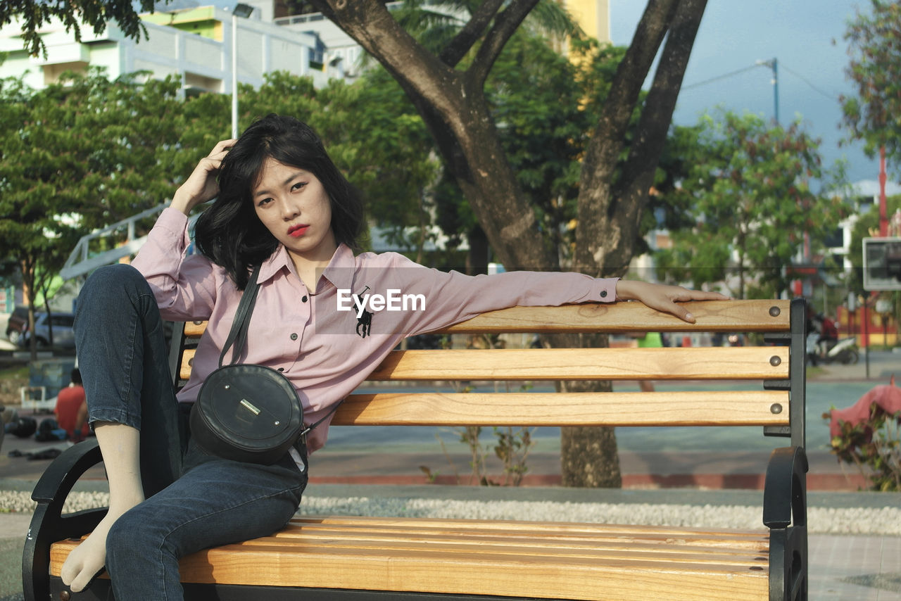 PORTRAIT OF WOMAN SITTING ON BENCH