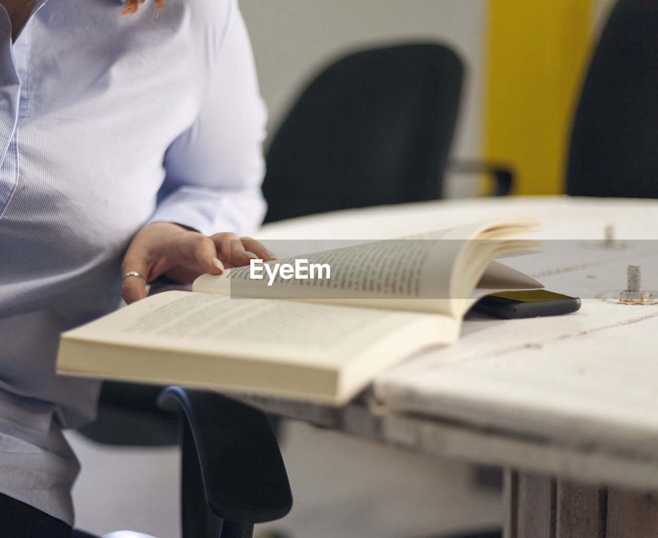 Midsection of woman reading book on table