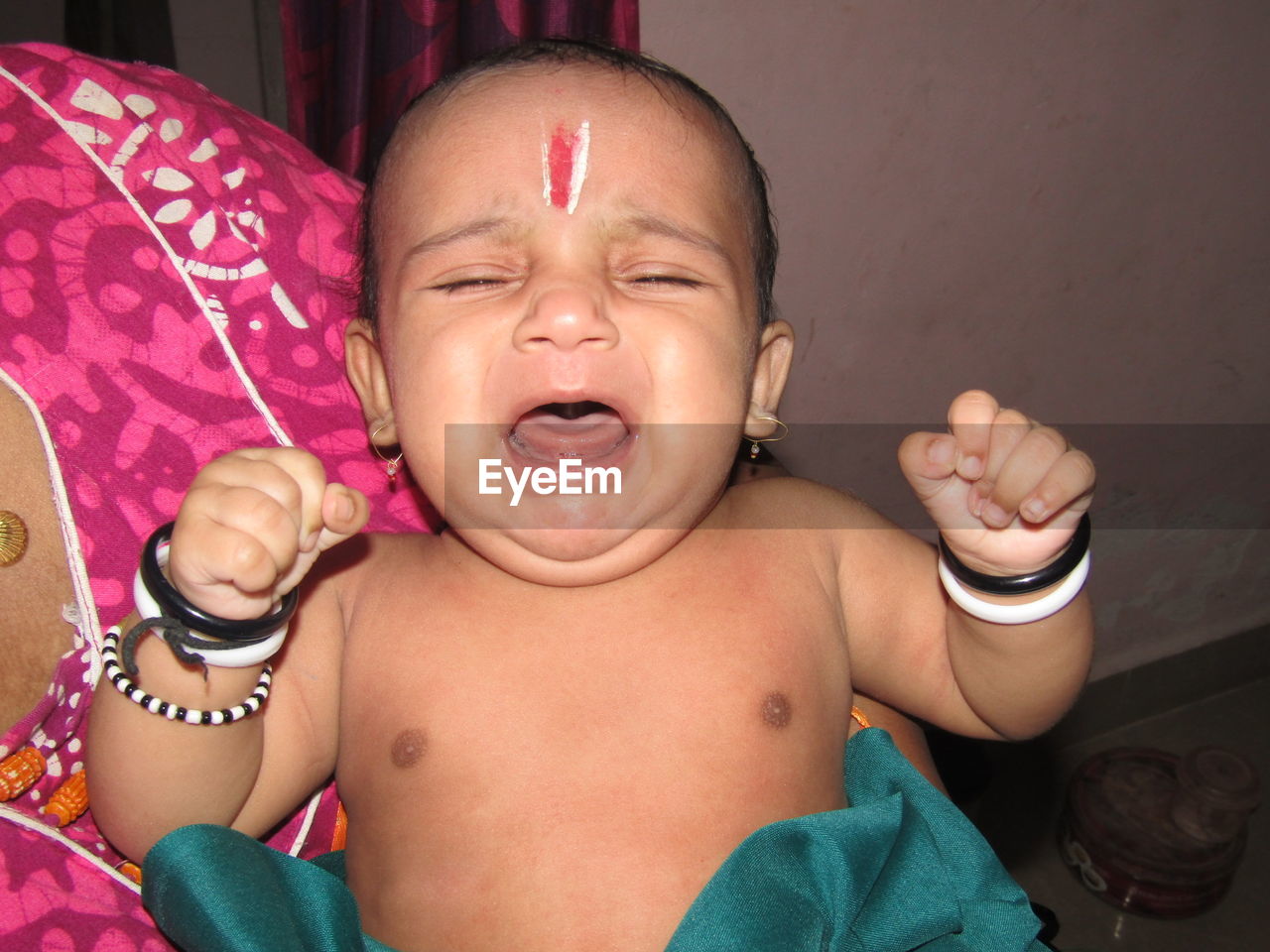 Midsection of mother carrying baby boy during krishna janmashtami at home