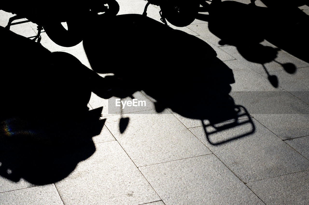 Shadow of parked motor scooters on street