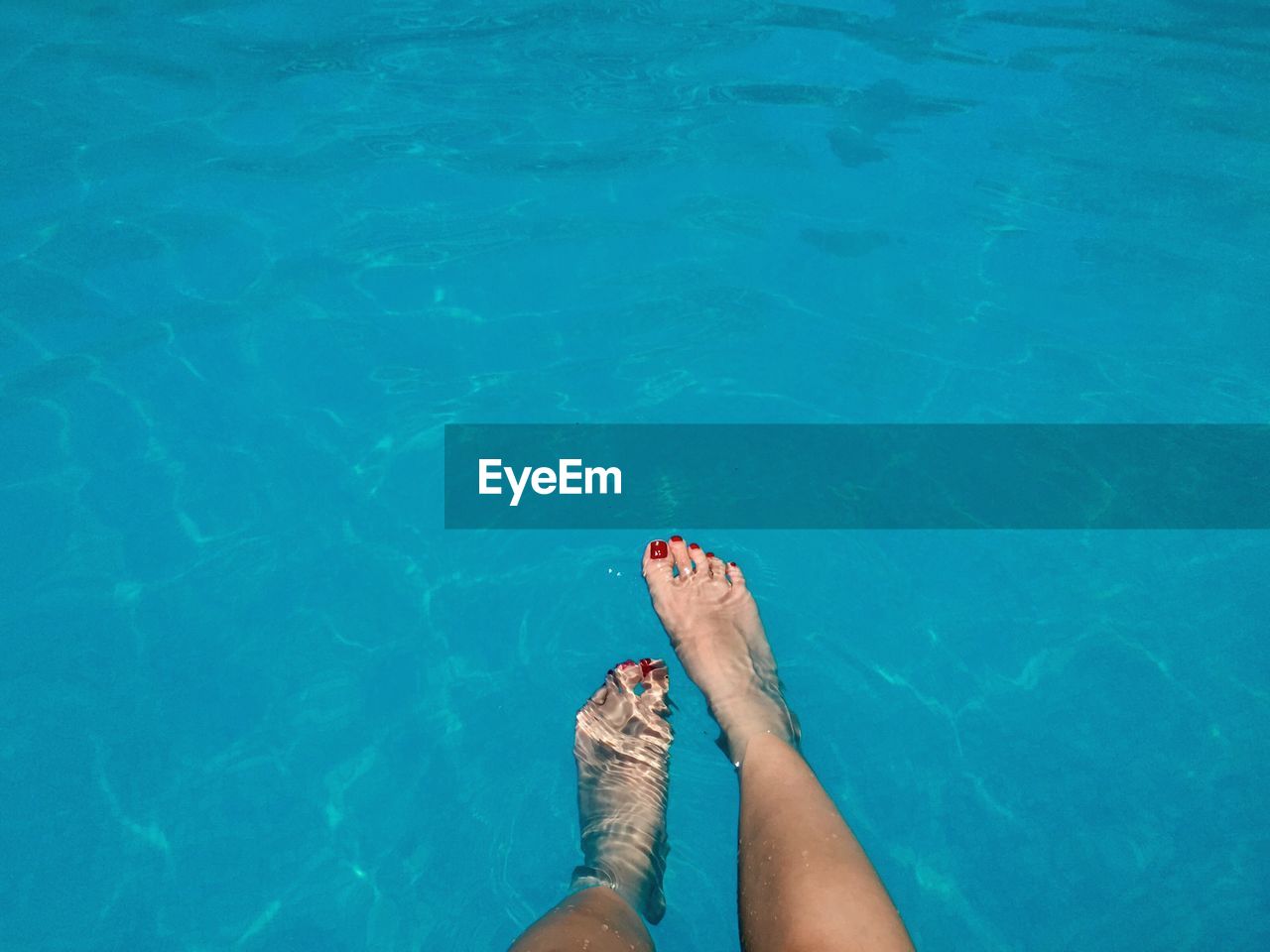 Low section of woman in swimming pool on sunny day