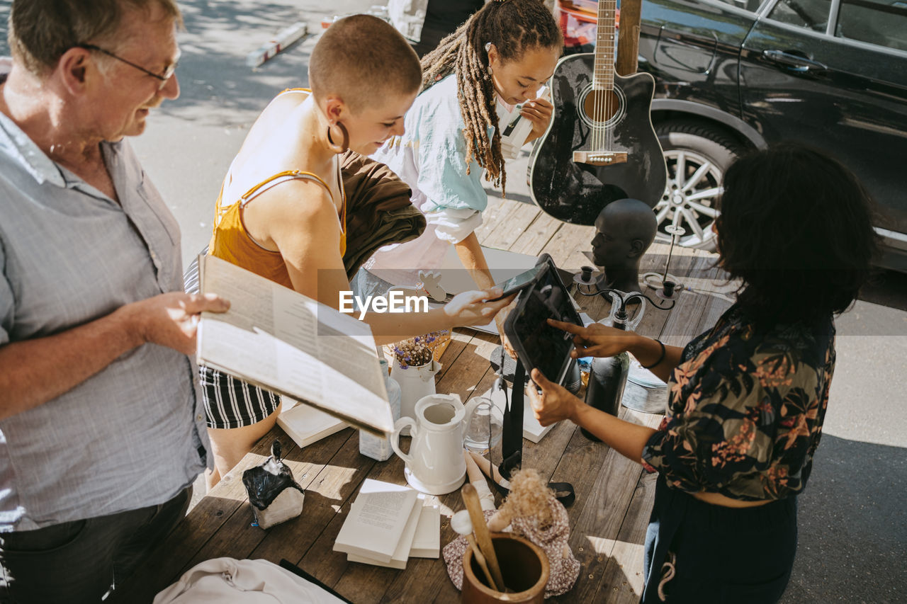 High angle view of owner processing online payment of female customer at flea market