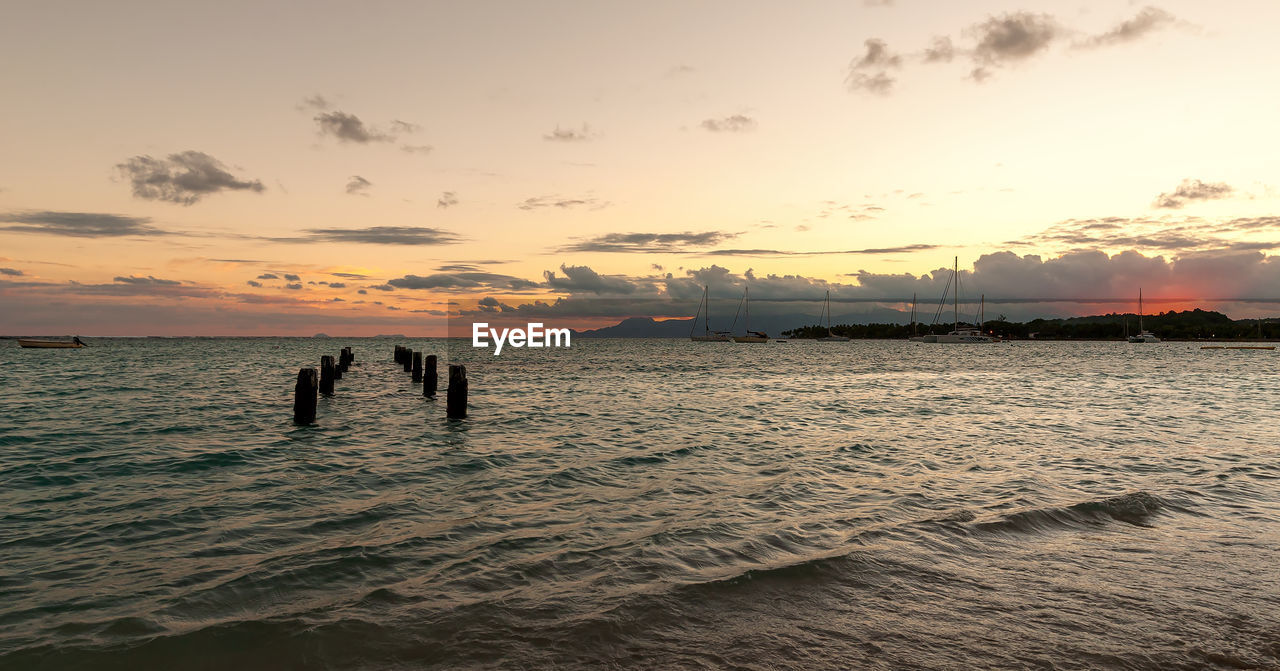 SILHOUETTE PEOPLE ON SHORE AGAINST SKY DURING SUNSET