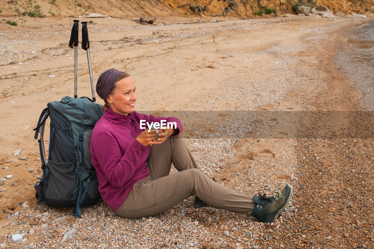 portrait of young woman sitting on sand at beach