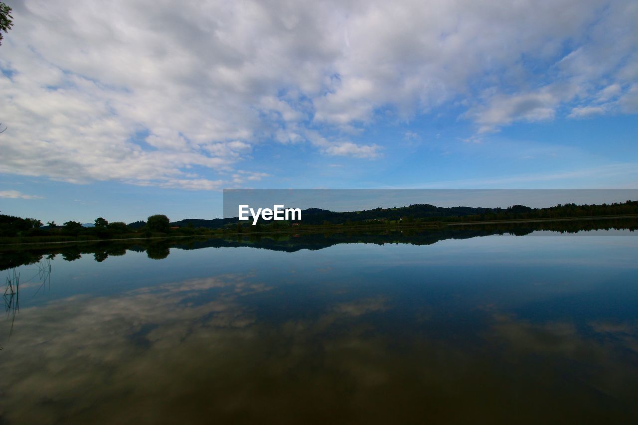 SCENIC VIEW OF CALM LAKE AGAINST CLOUDY SKY