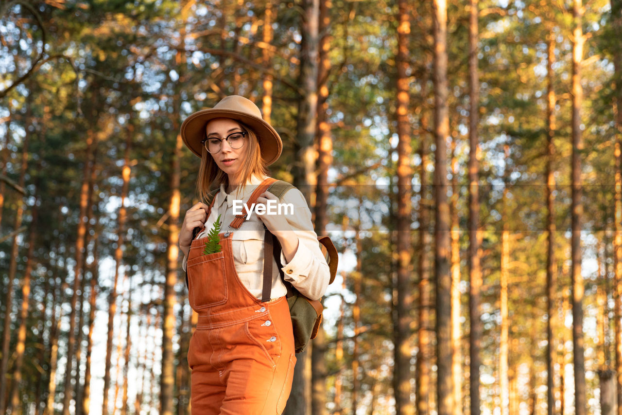 Woman botanist with backpack on ecological hiking trail. naturalist exploring wildlife ecotourism.