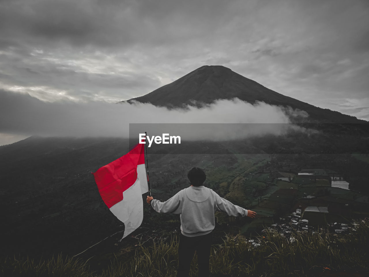 Rear view of men flag on mountain against sky