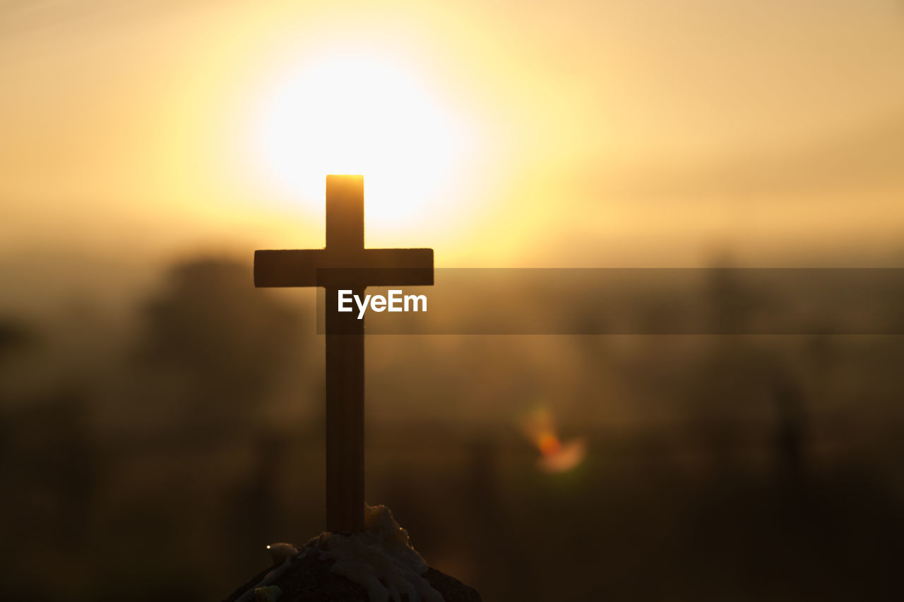 CLOSE-UP OF CROSS AT SUNSET