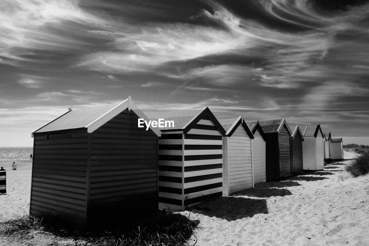 Beach huts against cloudy sky