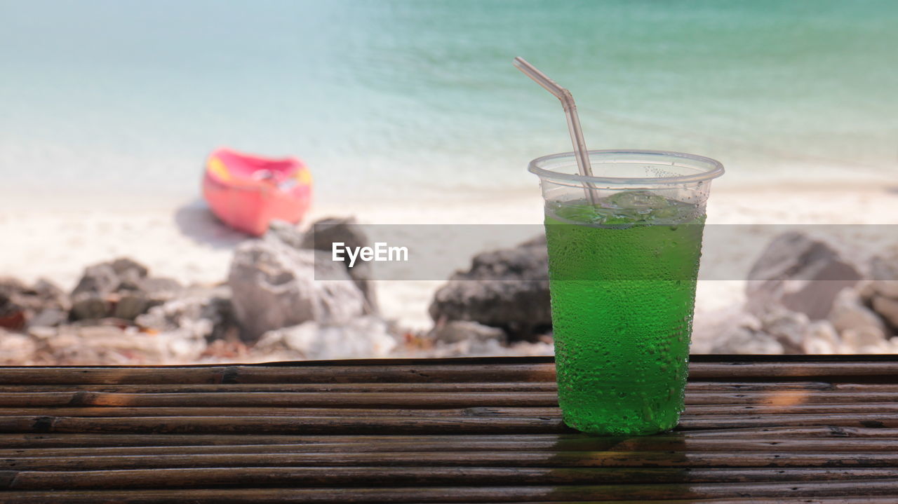 soft drink, beach, drink, refreshment, food and drink, land, water, sea, drinking glass, straw, nature, glass, drinking straw, household equipment, fruit, food, summer, focus on foreground, vacation, wood, trip, sand, freshness, no people, outdoors, sky, day, cocktail, alcohol, tropical climate, holiday, green, healthy eating, cold temperature, travel destinations, relaxation, beauty in nature, travel