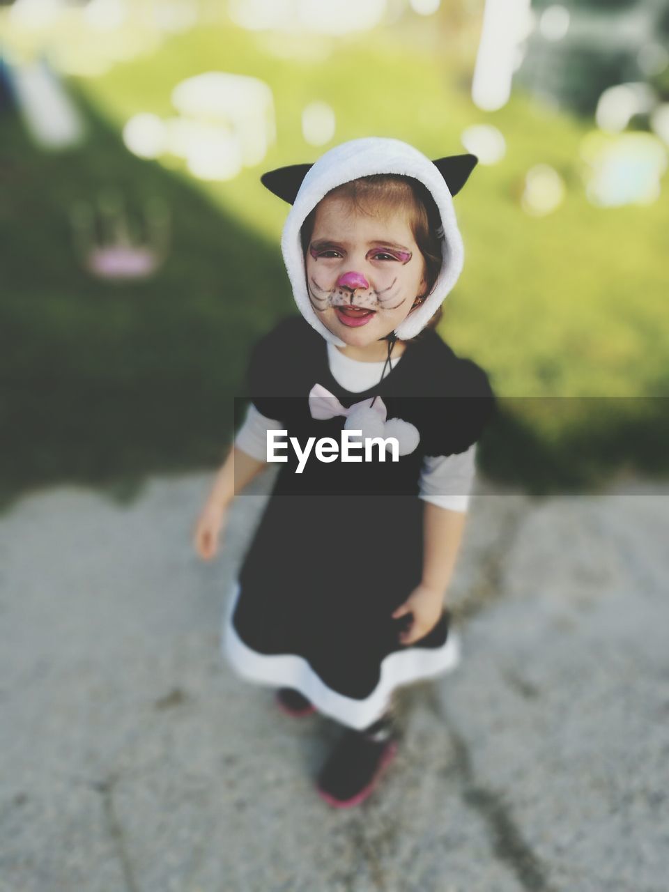 Portrait of girl with cat make-up and costume standing on footpath