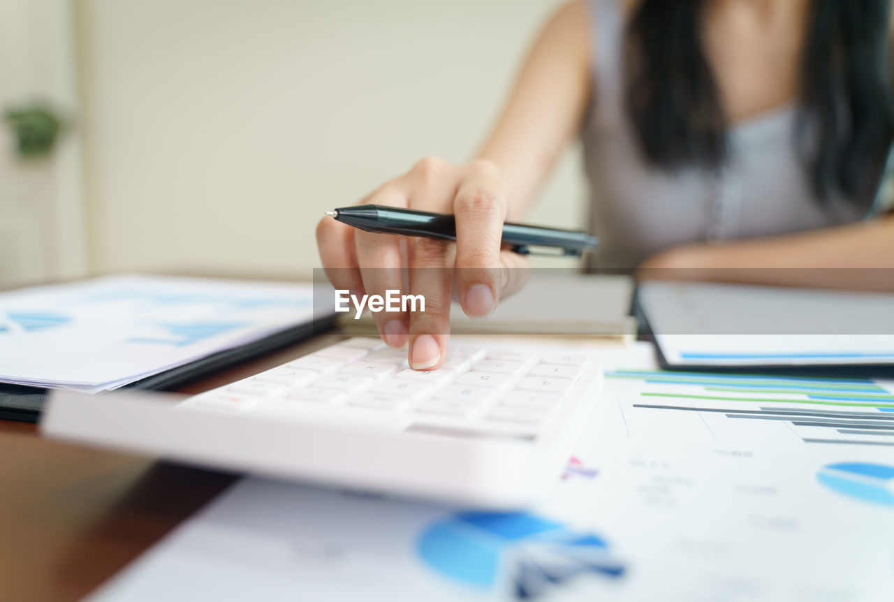 Businesswoman working from home with a calculator and financial report on wooden table.