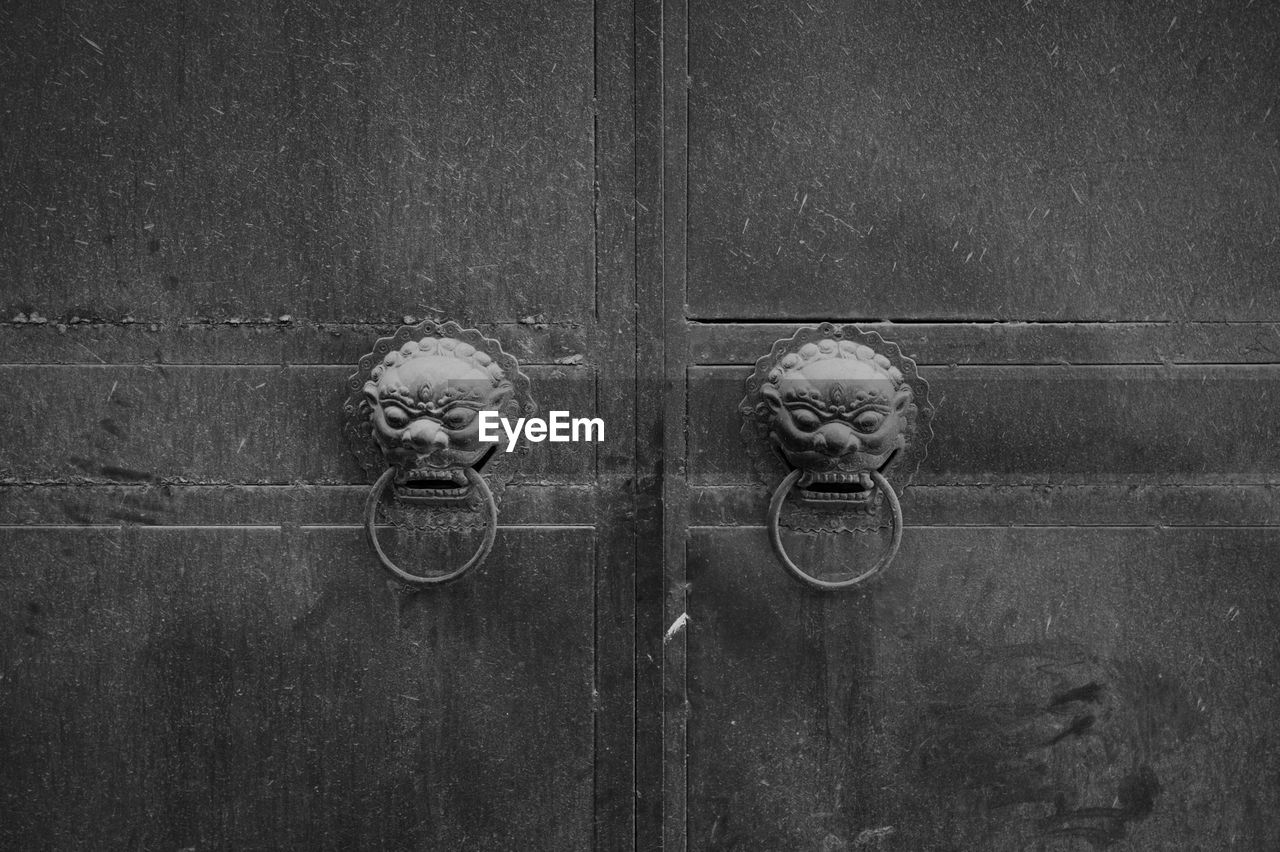 CLOSE-UP OF DOOR KNOCKER ON WOODEN WALL