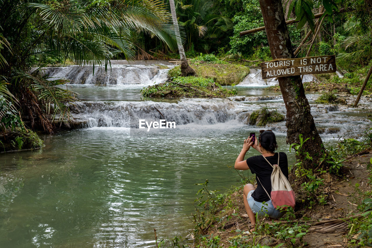 Woman photographing by stream