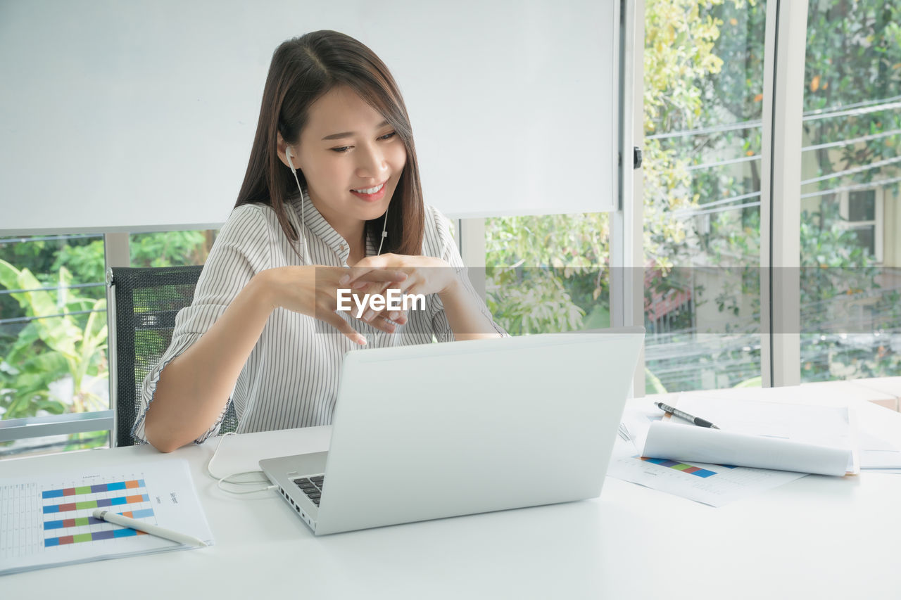 Business woman using laptop for video conferencing with colleagues at company office.