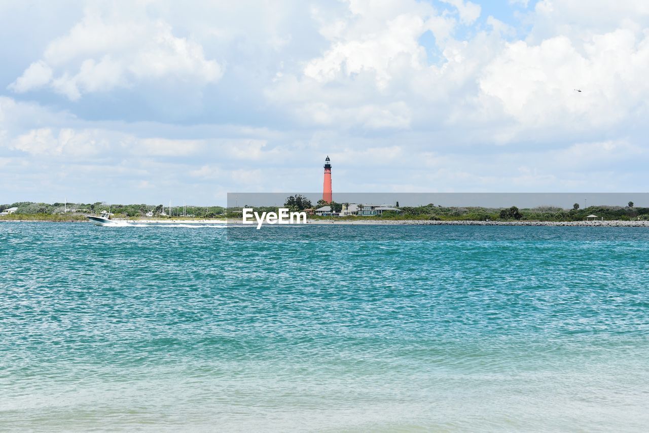 Lighthouse by sea against sky