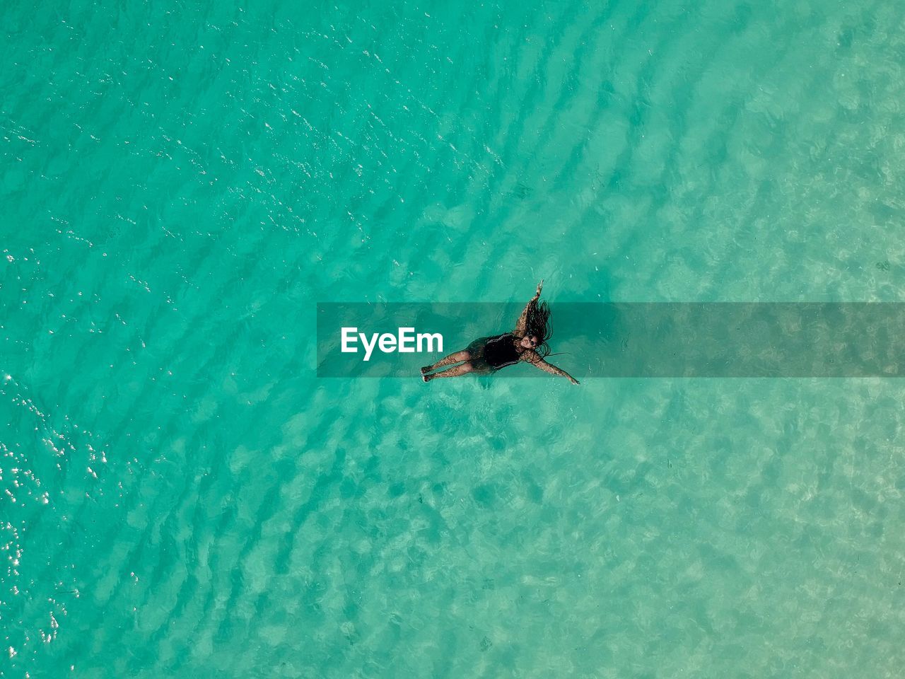 High angle view of woman floating on water with arms outstretched