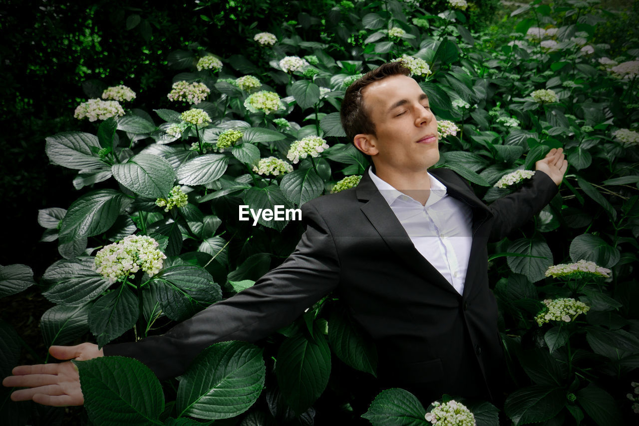Businessman with arms outstretched standing amidst plants