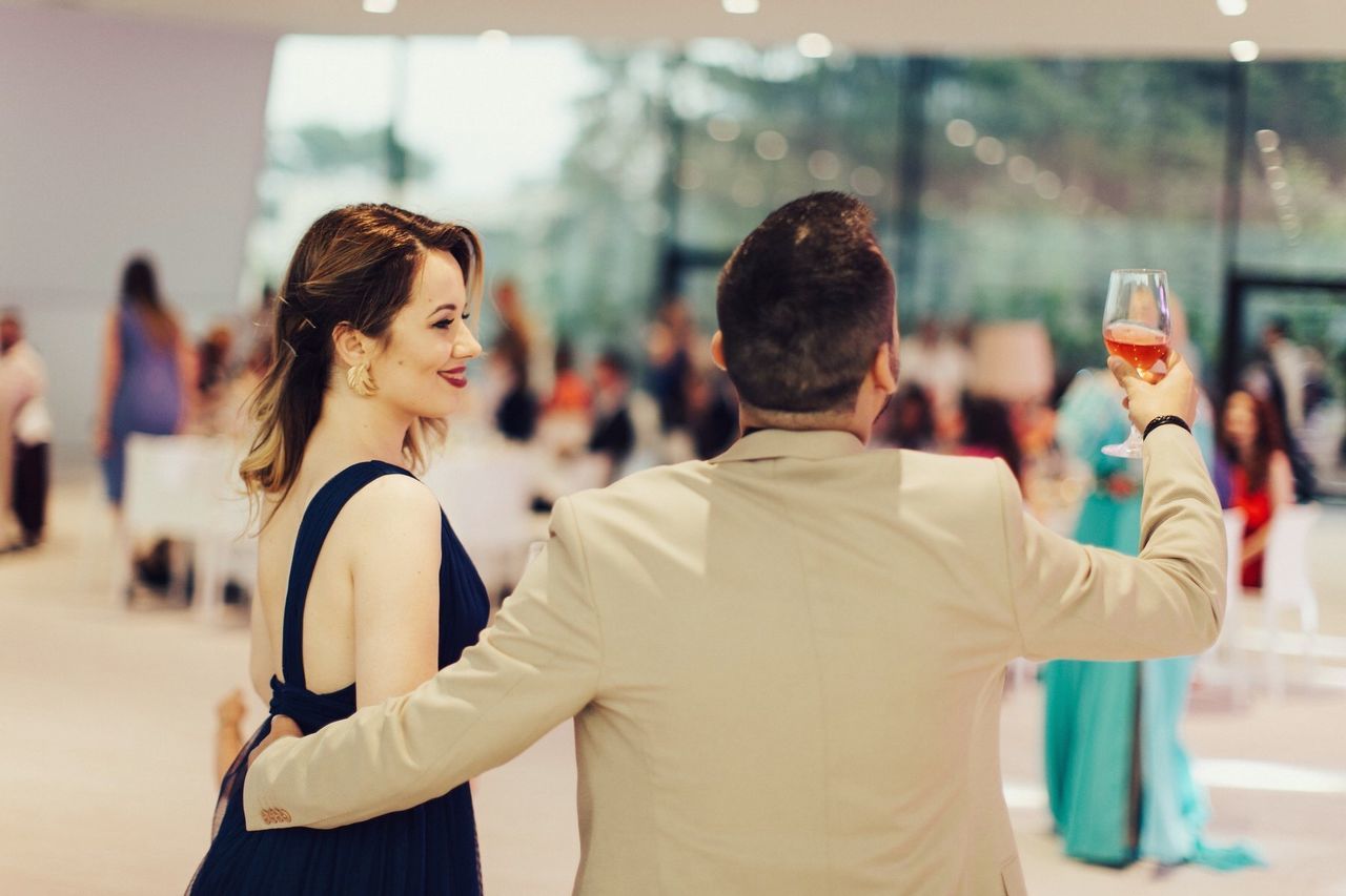 REAR VIEW OF COUPLE STANDING AT GLASS