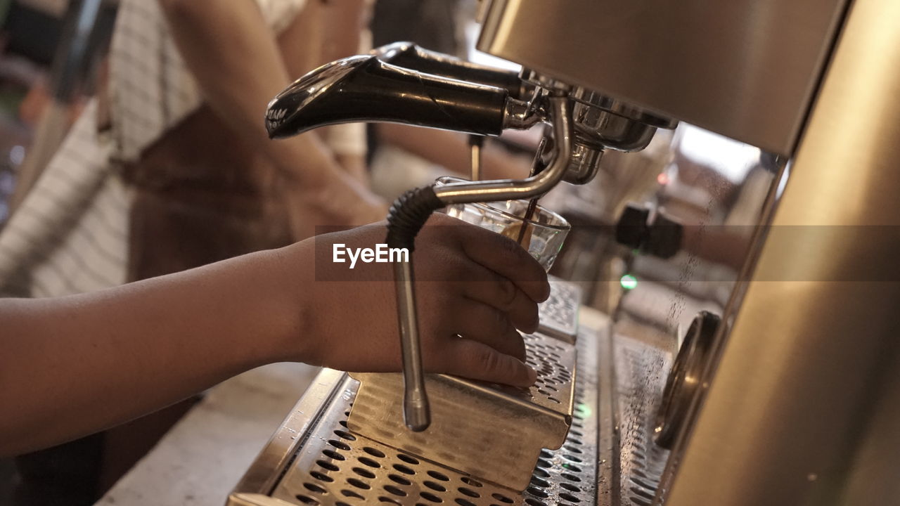 Close-up of person using coffee maker 