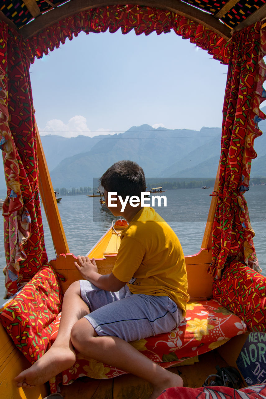 Rear view of boy sitting on boat 