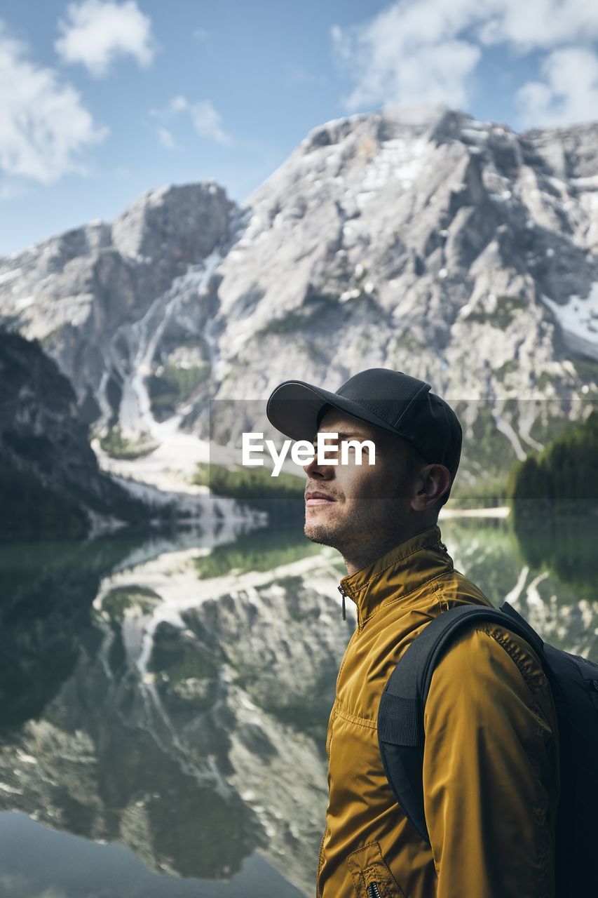 Backpacker looking at view by lake against mountains