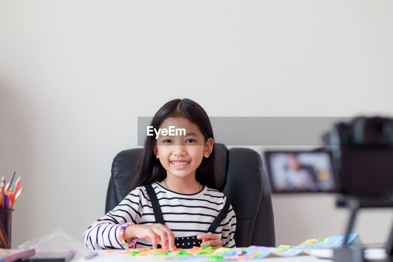 Portrait of smiling girl sitting by table at home