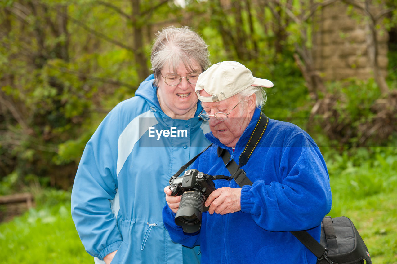 An elderly couple review photographs on the back of a dslr camera.